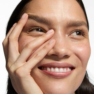 Close-up of a woman's face with one hand covering her eye on a white background