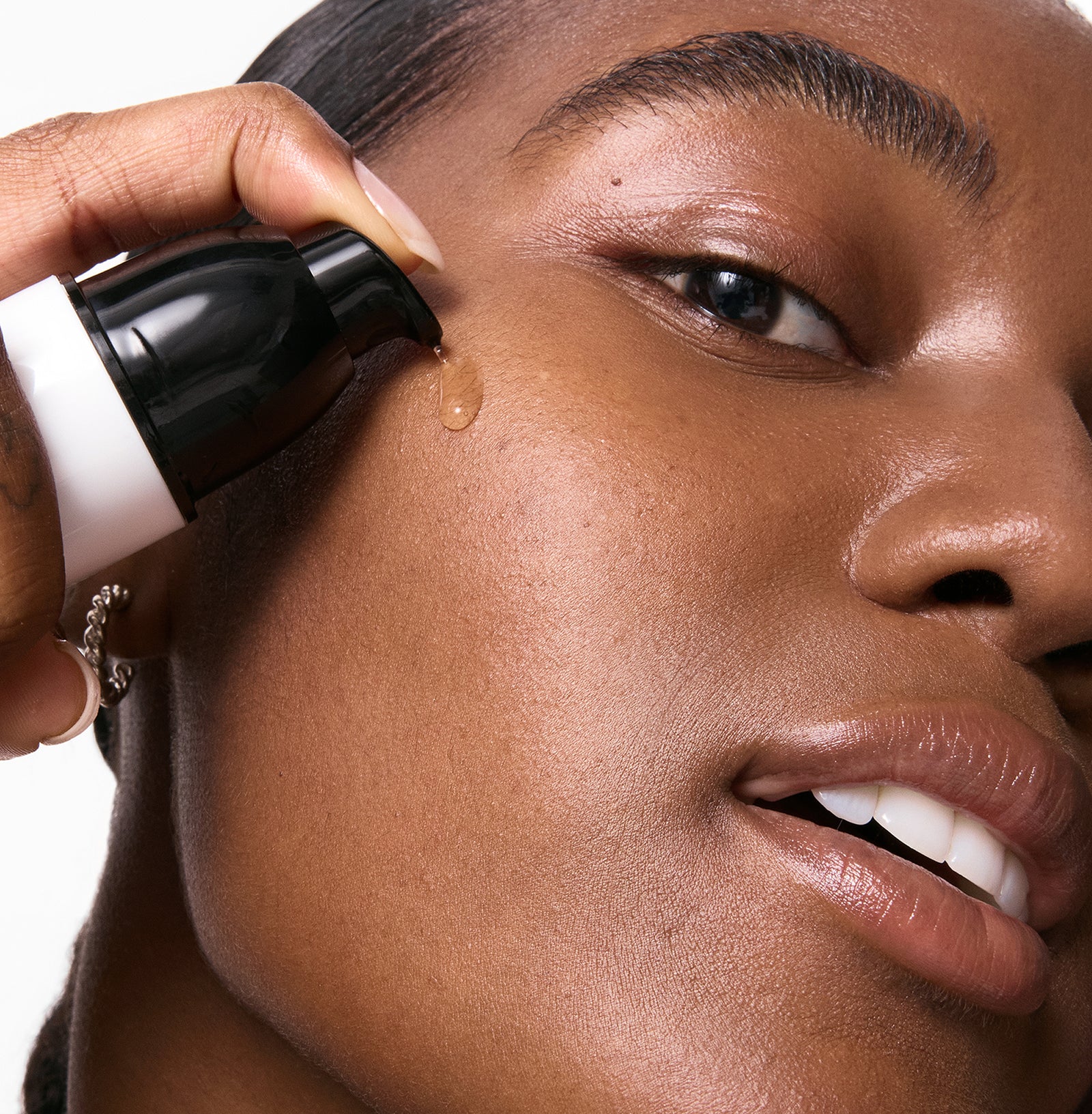 Person applying15% Vitamin C + EGF Serum to face with close-up focus on skin texture