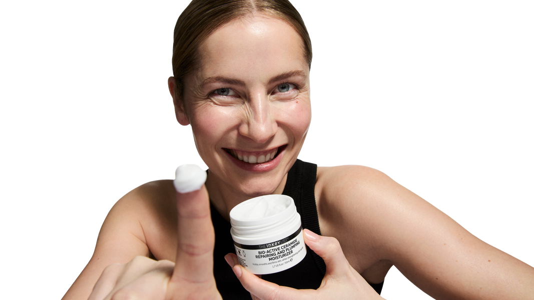 Woman holding a white container with a black label against a white background