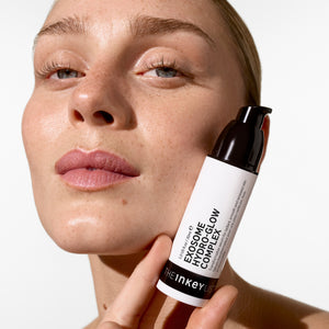 Woman holding a skincare product labeled 'Exosome Hydro Glow Complex' by The Inkey List.