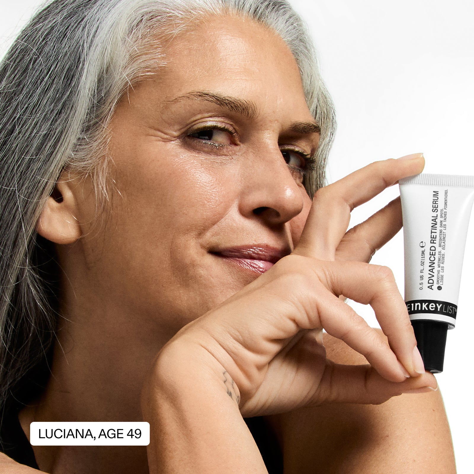 Woman with gray hair holding a skincare product, with text indicating her name and age.