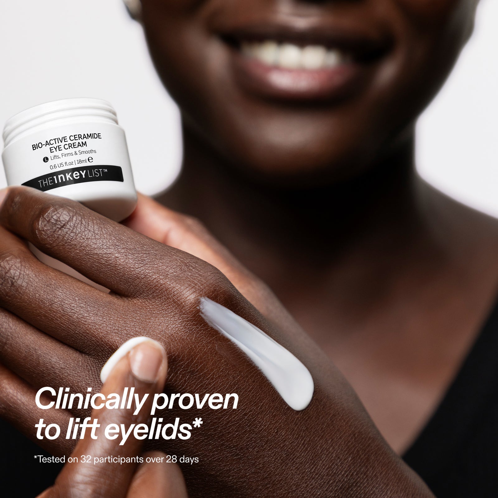 A close-up of a person holding a white jar of The Inkey List Bio-Active Ceramide Eye Cream while applying a thick white cream onto their hand. The text overlay reads 'Clinically proven to lift eyelids'.