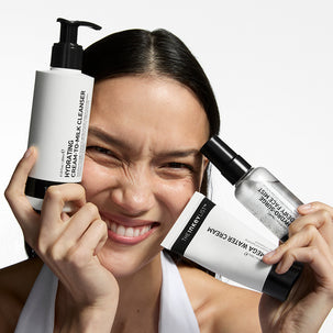 Woman holding skincare products with a neutral background