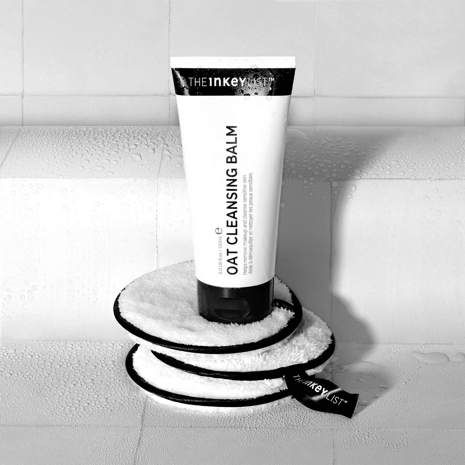 The Makeup Removal Duo shot in a bathroom with Oat Cleansing Balm sitting on top of a pile of Cotton Pads
