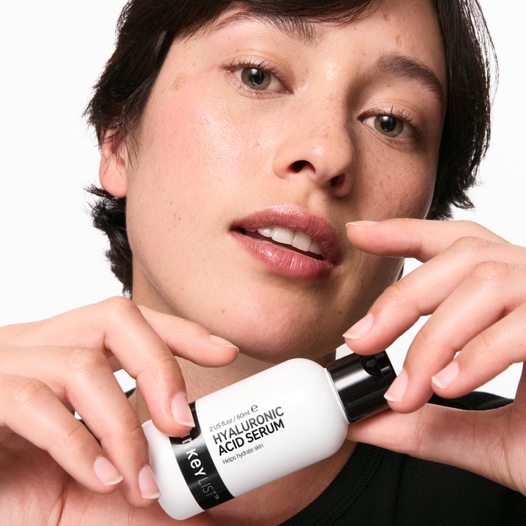 Person holding a bottle of INKEY Hyaluronic Acid Serum close to their face.