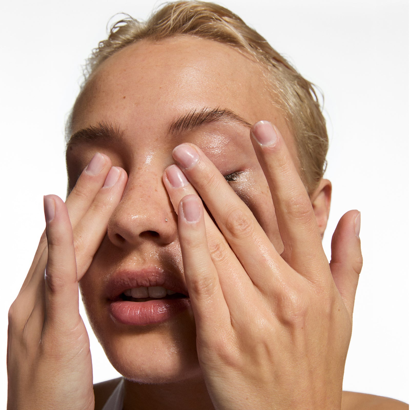 Person covering their face with their hands on a white background