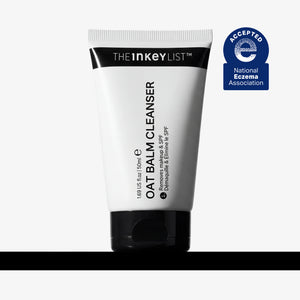 A white squeeze tube of The Inkey List Oat Balm Cleanser with a black cap, shown on a light gray background with a black horizontal bar at the bottom and a blue National Eczema Association Accepted badge on the upper right.