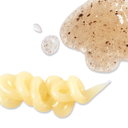 Close-up of beige scrub and cream with droplets on a white background