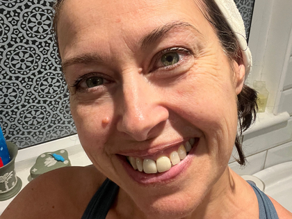 Woman smiling at the camera with a patterned wall in the background
